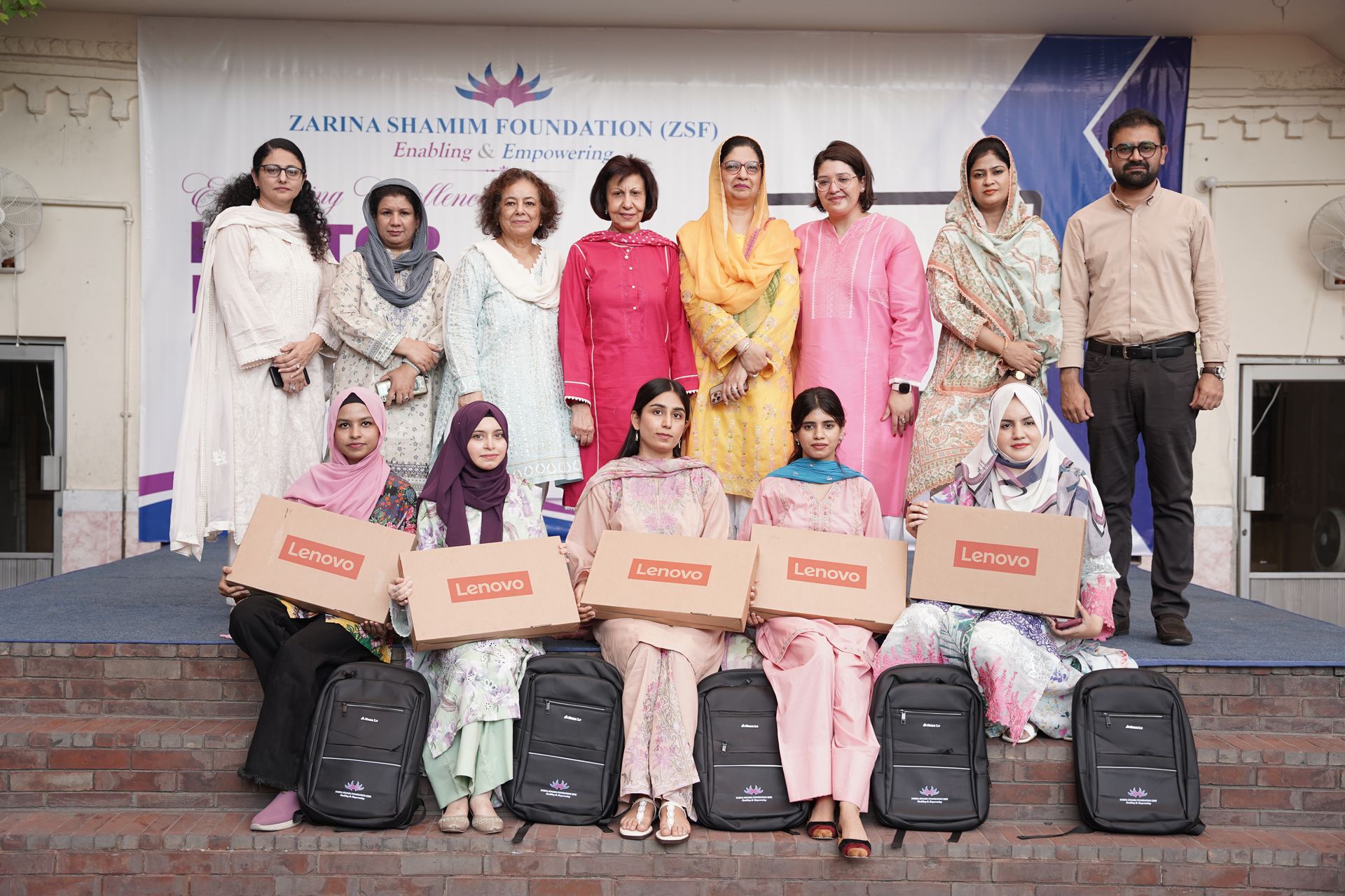 Scholarship recipients holding laptop boxes on stage