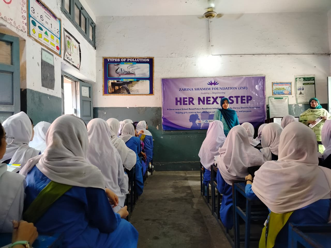 Students seated in rows facing the Her Next Step banner